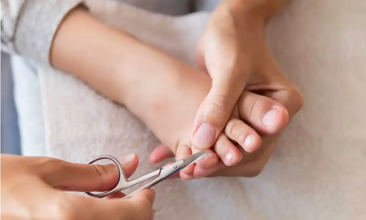 Pessoa cortando a unha do pé com tesoura, mostrando o corte redondo