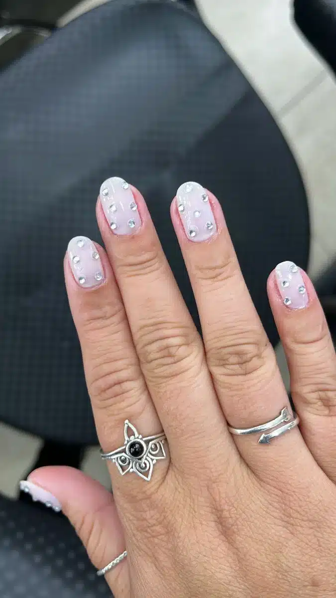 Unhas arredondadas com decoração de strass, criando um visual glamouroso e moderno.