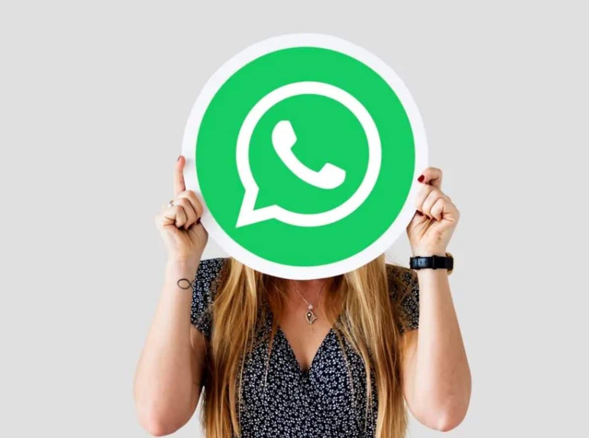 Mulher segurando um grande ícone do WhatsApp na frente do rosto.