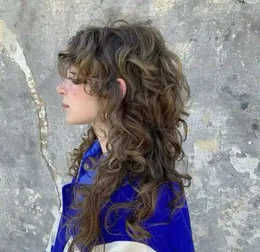 "Mulher com cabelo cacheado e ondulado, usando corte wolfcut, um estilo moderno e despojado."