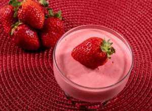 Delicioso mousse de morango fit com morangos frescos sobre uma base cremosa de mousse.