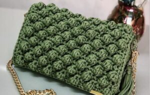 Bolsa de crochê verde com o ponto pipoca, uma técnica que cria uma textura tridimensional incrível.