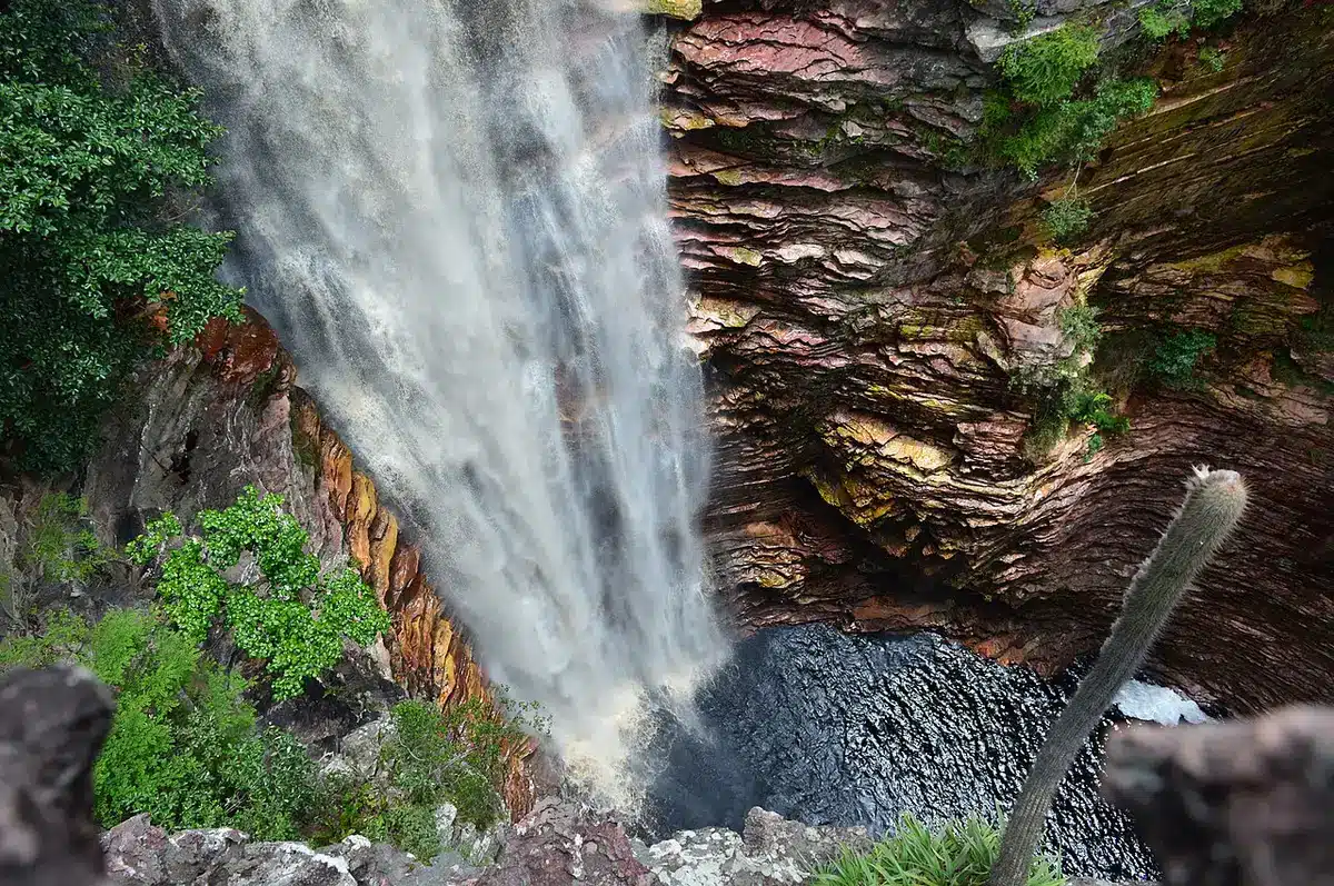 Vista impressionante da Cachoeira do Buracão, com sua queda d'água poderosa e rodeada por paredes de rochas coloridas.
