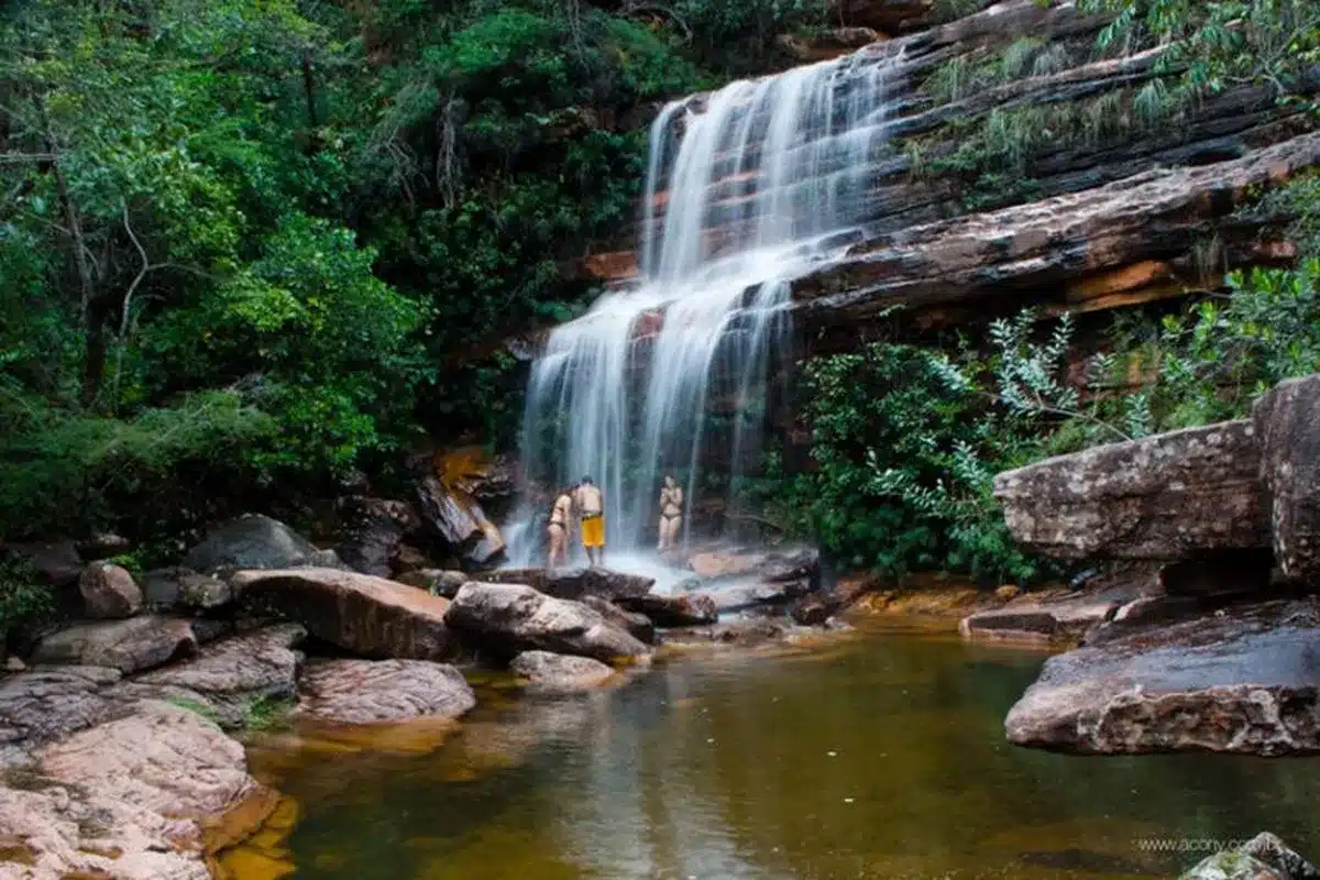 Visitantes aproveitam a beleza da Cachoeira da Primavera, em Lençóis, com sua queda d'água em meio à vegetação exuberante.
