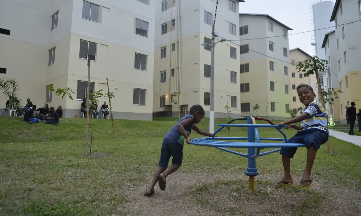 "Crianças brincando em um parque dentro de um complexo habitacional, simbolizando a simplicidade e praticidade do processo de inscrição."