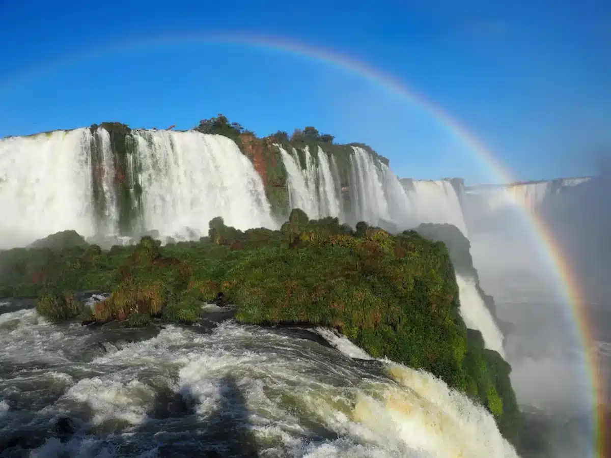 Vista das Cataratas do Iguaçu com arco-íris ao fundo, uma das Sete Maravilhas Naturais do Mundo.