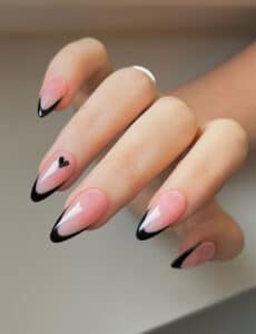Unhas com alongamento em acrigel em formato amendoado, esmalte rosa com pontas pretas e detalhe de coração.