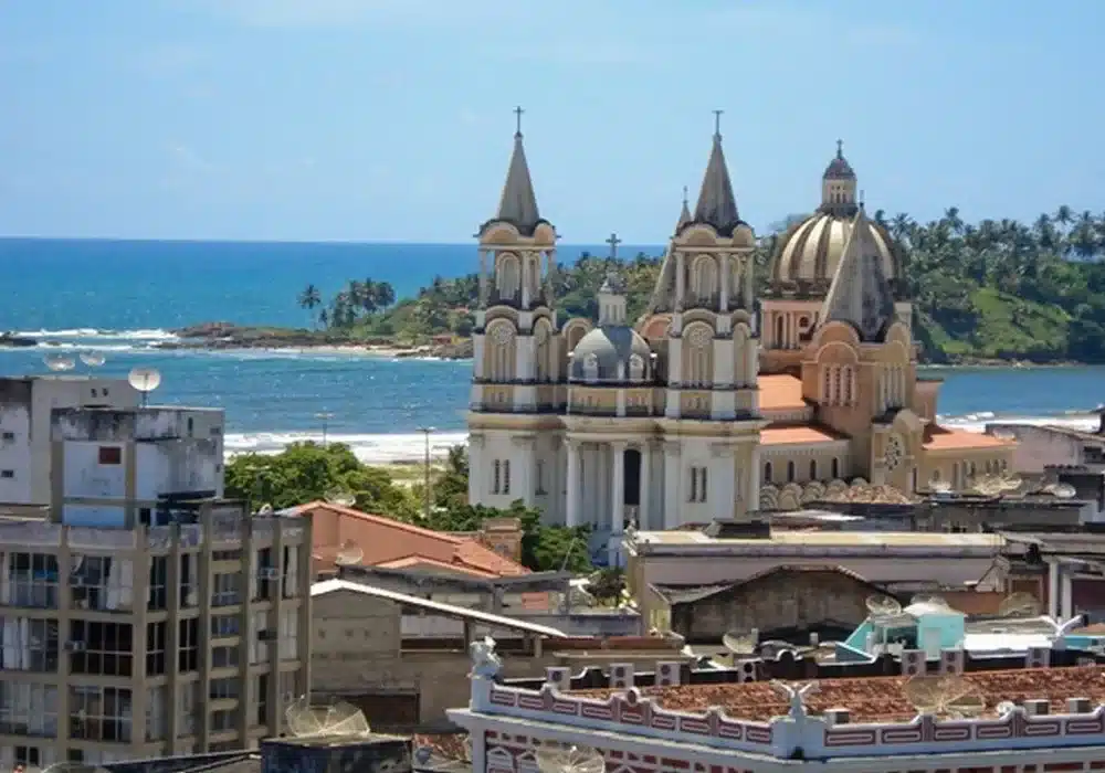 Vista panorâmica da cidade de Ilhéus, Bahia, com uma igreja histórica e o mar ao fundo.