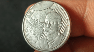 Moeda de 50 centavos com erro de cunho quebrado, mostrando defeito visível na face da moeda.