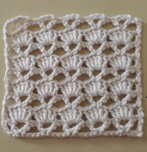 Ponto fantasia em crochê com detalhes florais, criado com fio branco e técnicas de tecelagem.