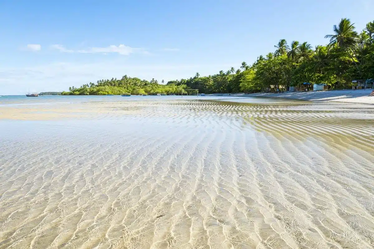 Praia tranquila em Santo André, Bahia, com águas cristalinas e areia dourada.