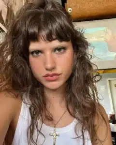 Imagem de corte mullet no estilo shaggy hair, com cabelo ondulado e franjas.