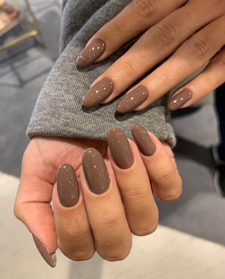 Unhas pintadas com esmalte cor mocha mousse em mãos femininas