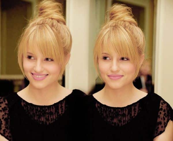 Mulher com cabelo preso em coque e franja meia-lua, com fios mais longos nas laterais