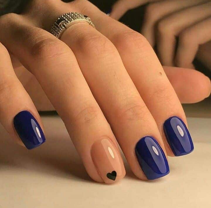 Unhas pintadas com esmalte azul oceano e detalhe em nude com coração preto