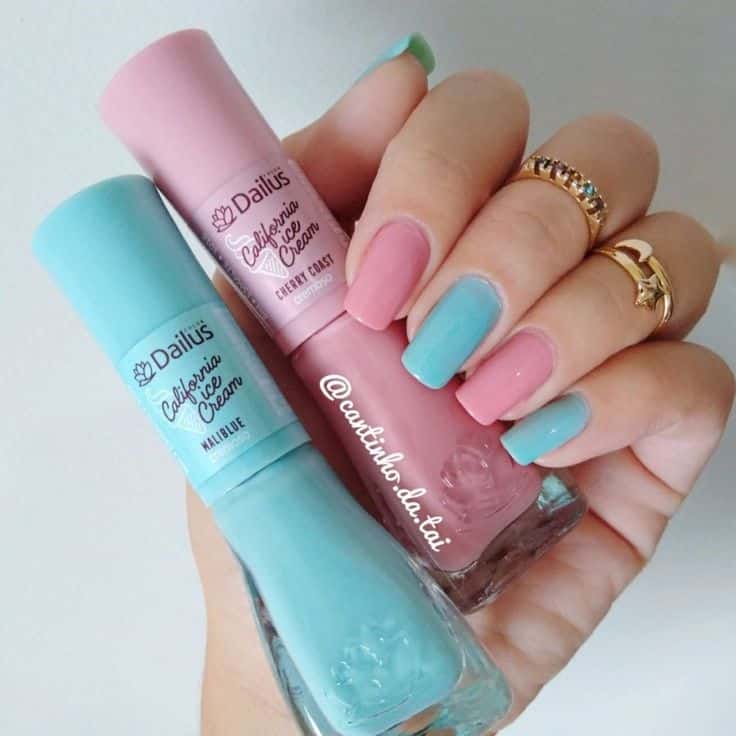 Unhas com esmaltação rosa candy e azul bebê segurando vidrinhos da marca Dailus