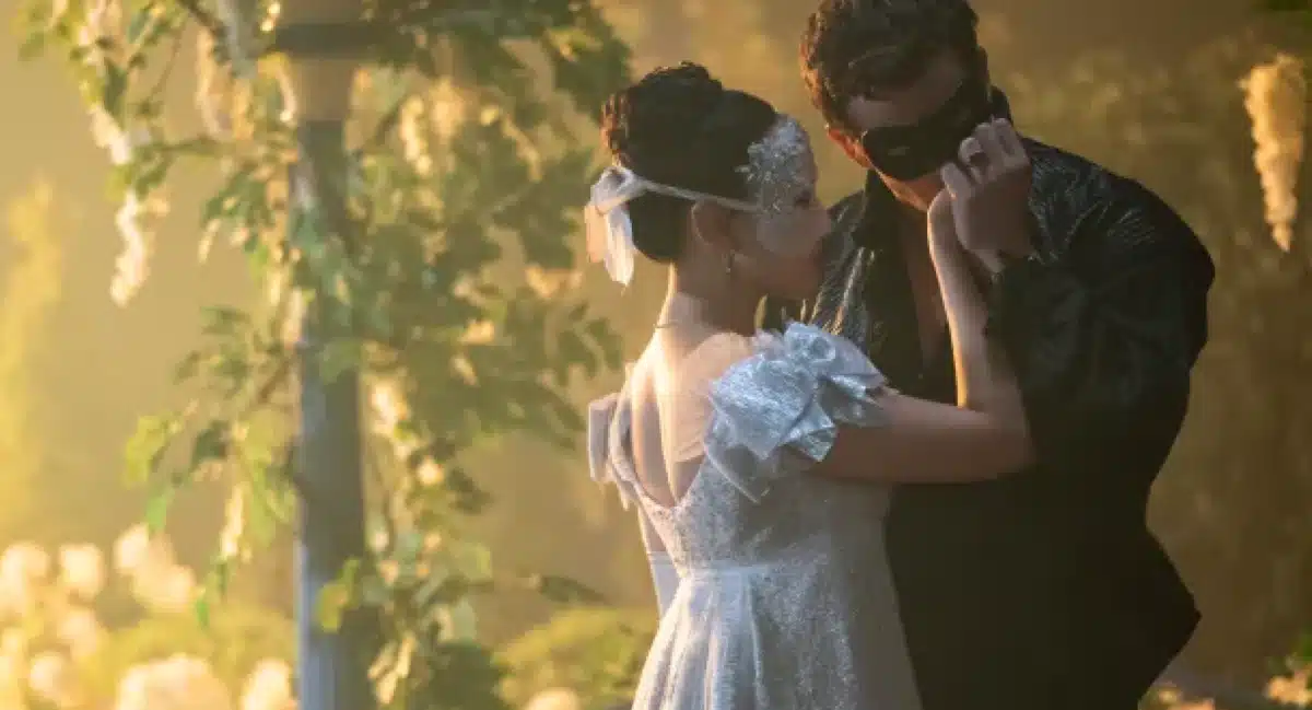 Cena romântica de baile de máscaras com um casal em trajes de época na série Bridgerton.