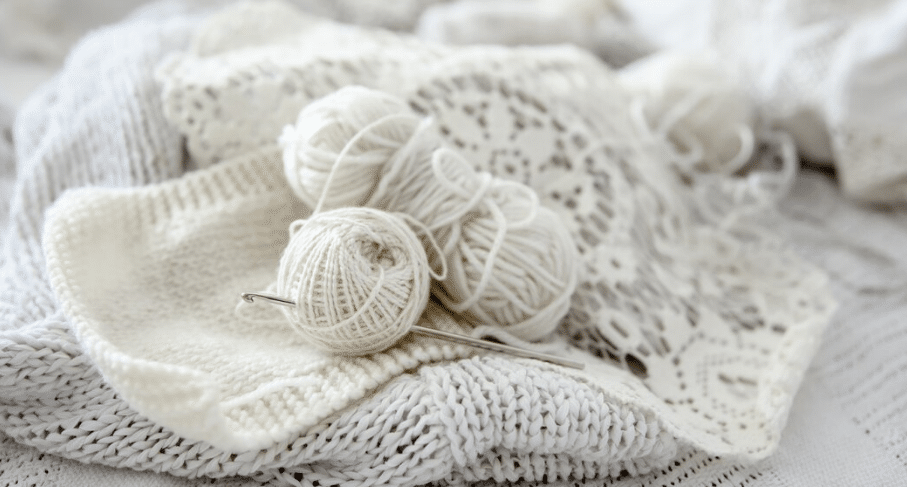 Novelos de linha branca sobre tecidos de crochê e tricô artesanal