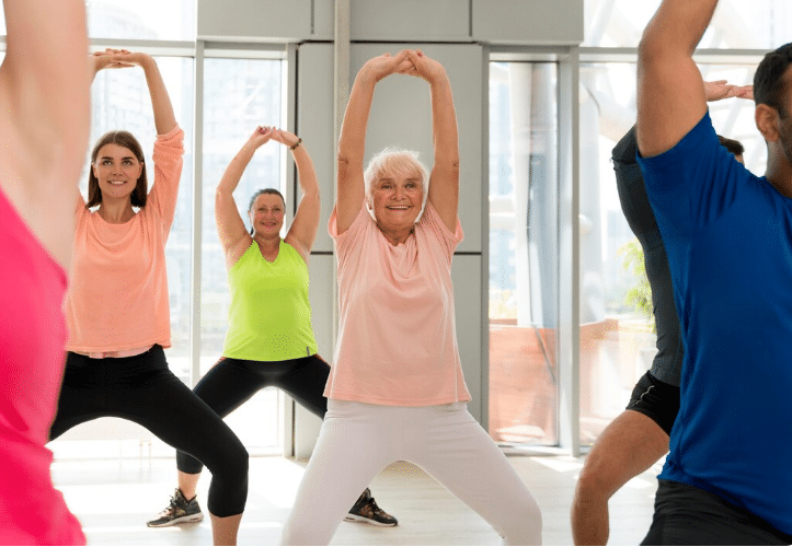 Grupo de pessoas, incluindo idosos, praticando zumba em aula coletiva