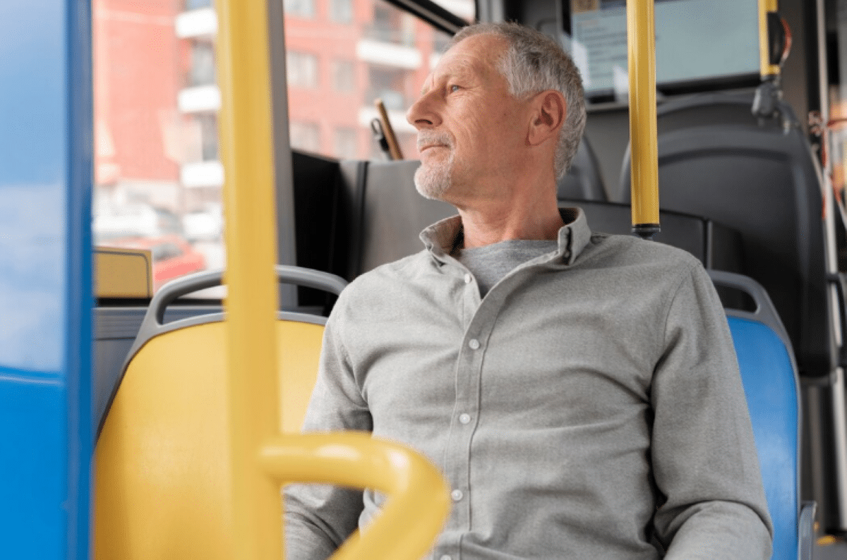 Idoso pensativo olhando pela janela de ônibus durante a viagem