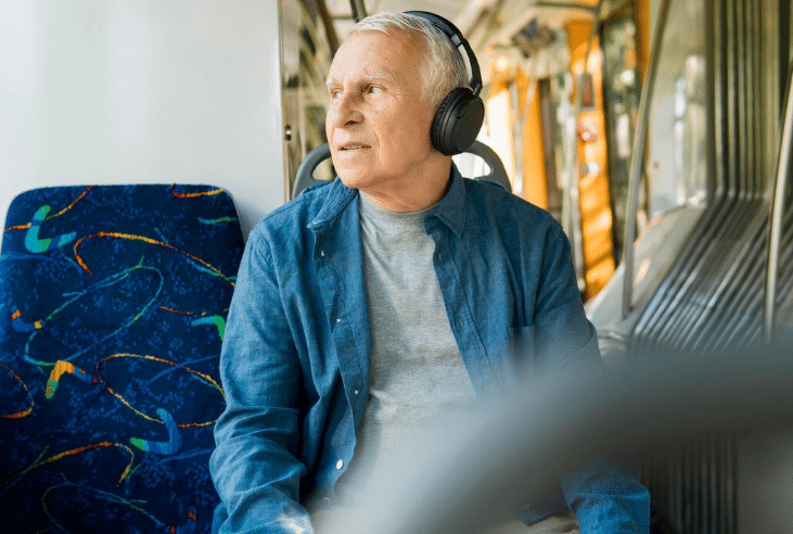Idoso ouvindo música com fones enquanto viaja de transporte público