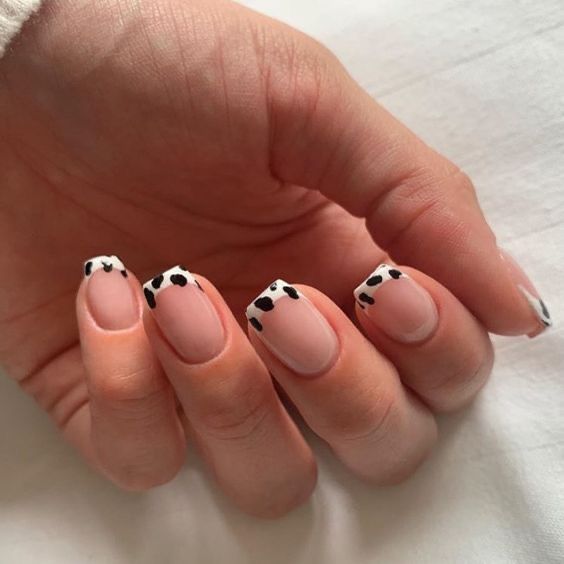 Unhas com francesinha de vaca, com detalhes pretos no formato de manchas sobre fundo nude.