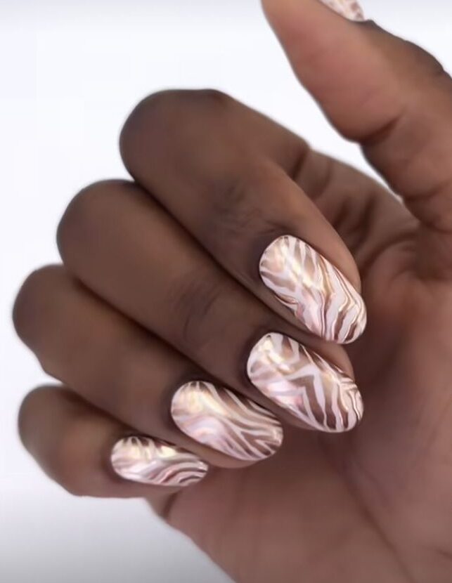 Unhas com estampa metalizada de zebra em tons de rosa e branco.