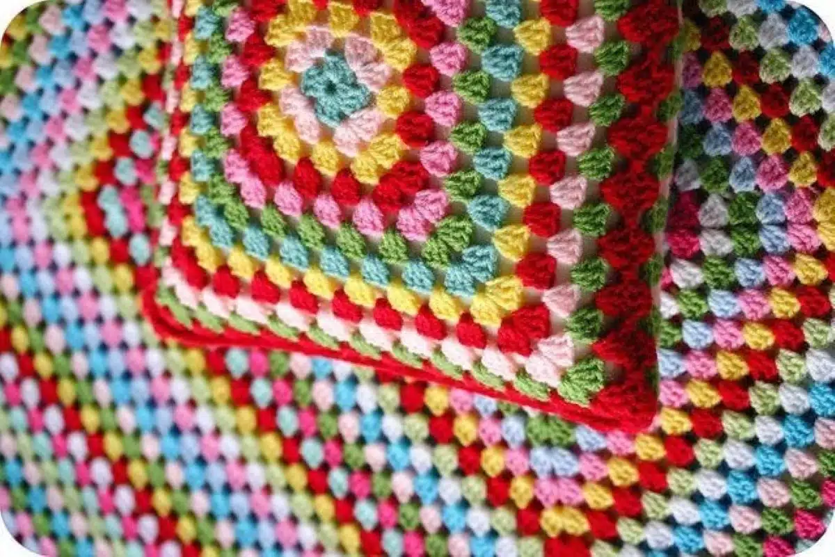 Almofadas e mantas coloridas feitas em crochê com pontos detalhados e texturizados.