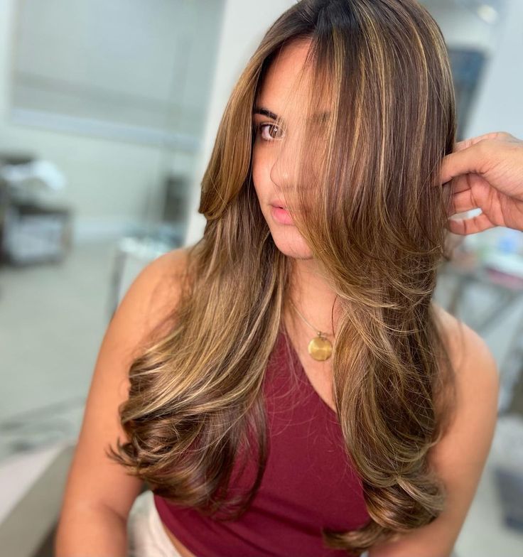 Mulher com cabelo longo, ondulado nas pontas e franja longa em camadas