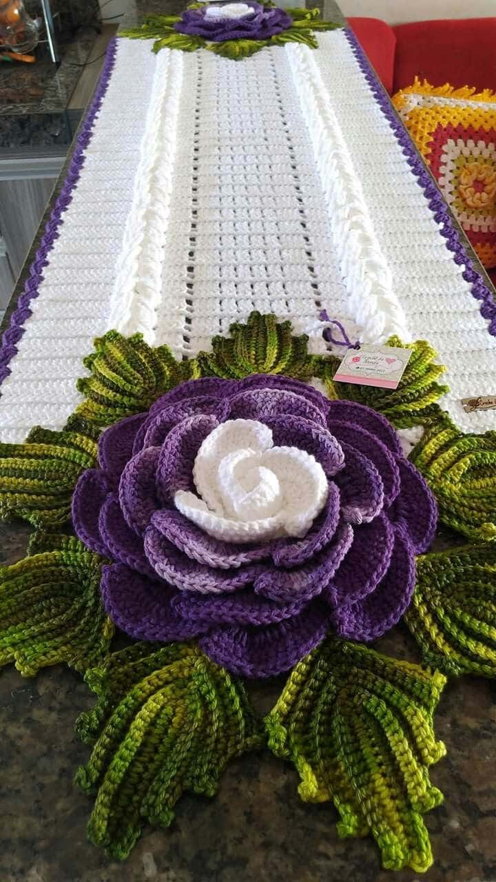 Caminho de mesa em crochê com grande flor roxa e folhas verdes detalhadas