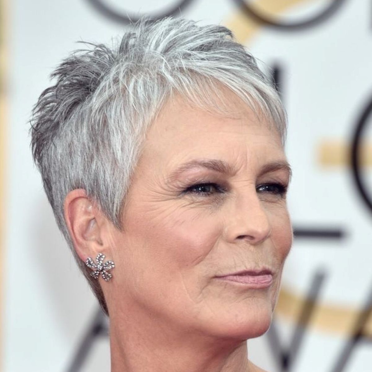 Mulher madura com corte de cabelo pixie grisalho, estilizado e moderno.