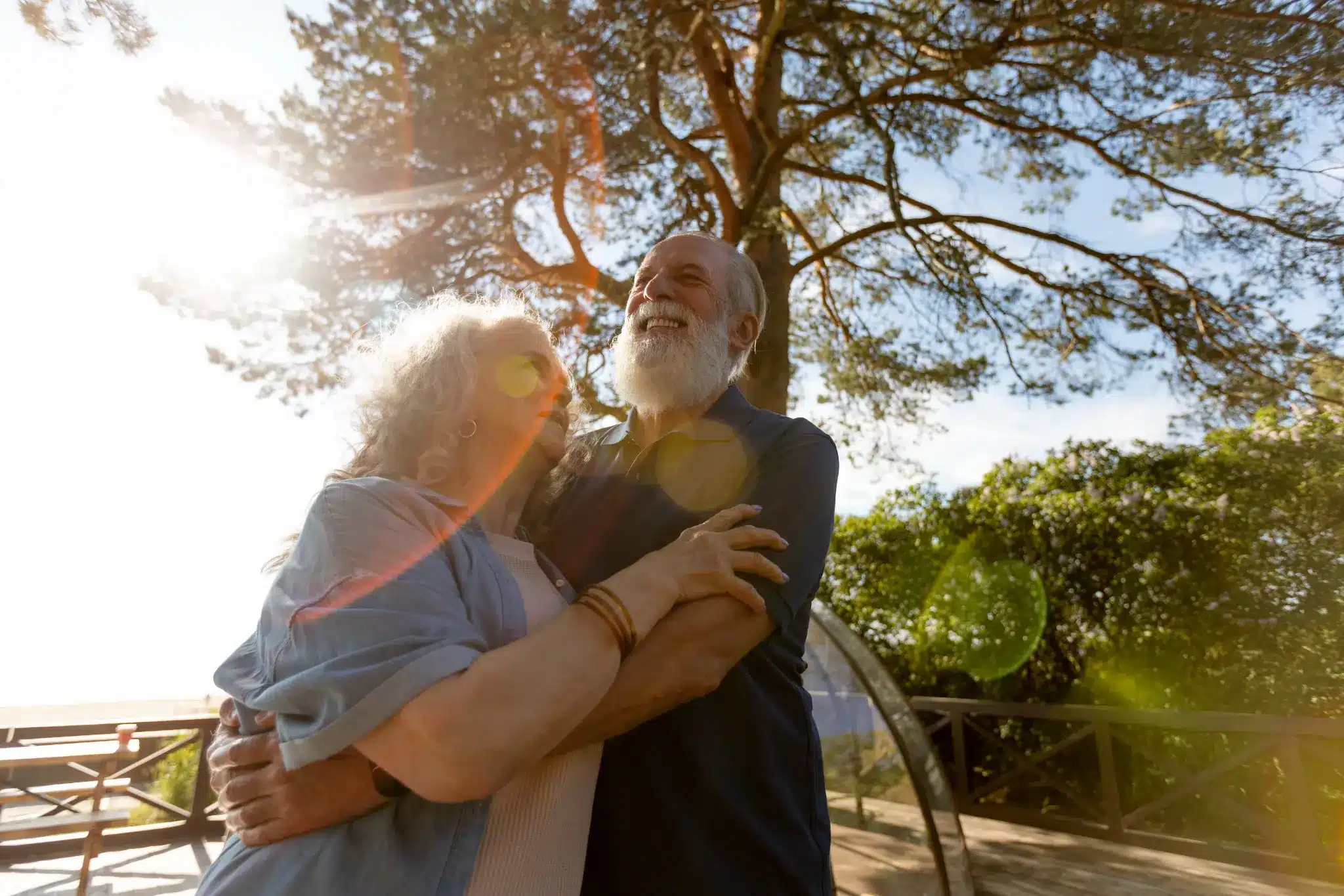 Casal idoso feliz abraçado ao ar livre, irradiando alegria e conexão emocional.