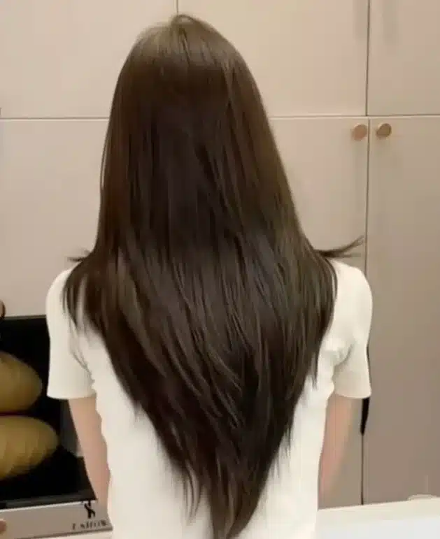 Mulher de costas exibindo cabelo longo com corte em camadas no formato em V.