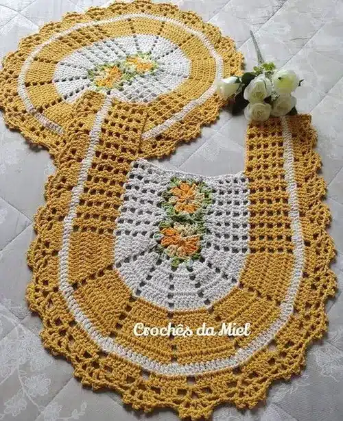 Conjunto de crochê com detalhes florais em amarelo, branco e verde, decorado com pérolas
