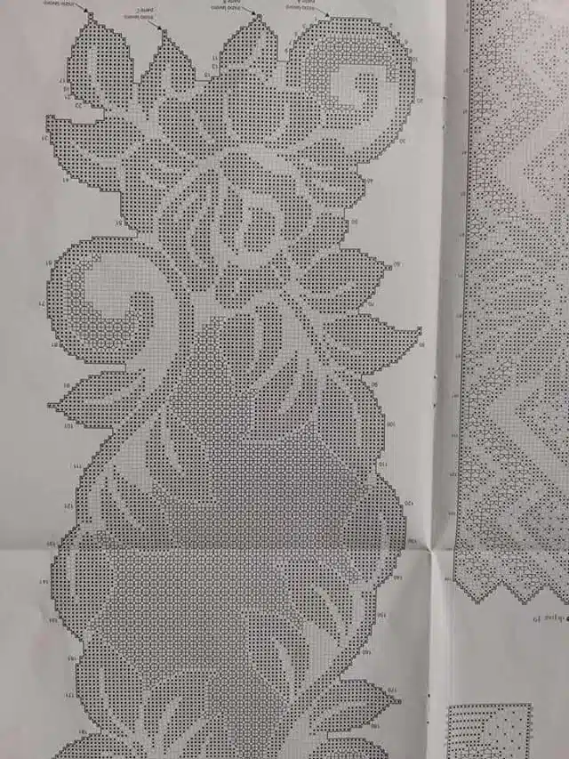 Diagrama de crochê em filet com detalhes florais, representando um trabalho manual delicado e preciso.