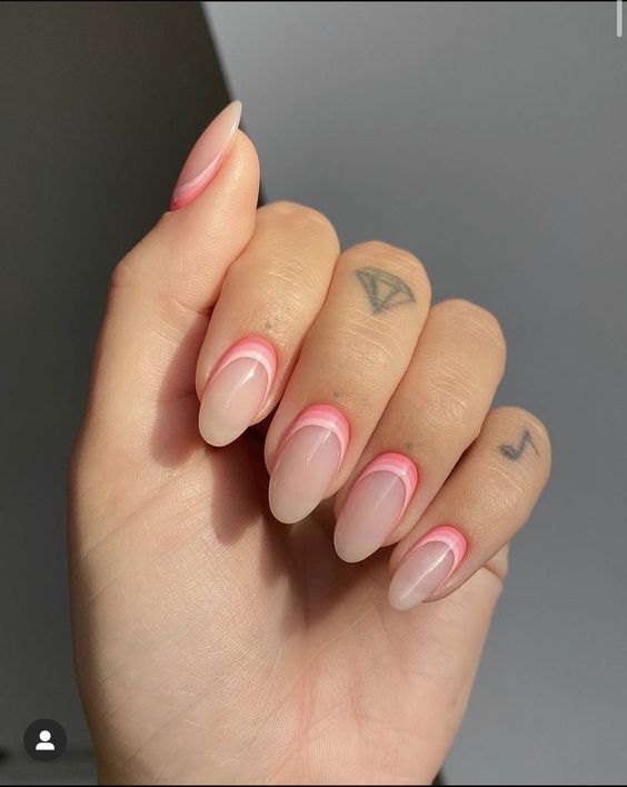 Unhas com francesinha invertida em tom de rosa claro, com base nude e contorno rosa vibrante.