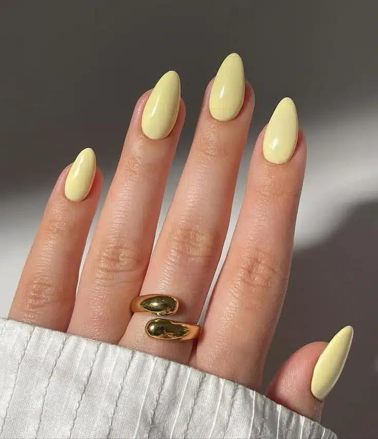 Unhas longas em formato amendoado pintadas com esmalte amarelo manteiga