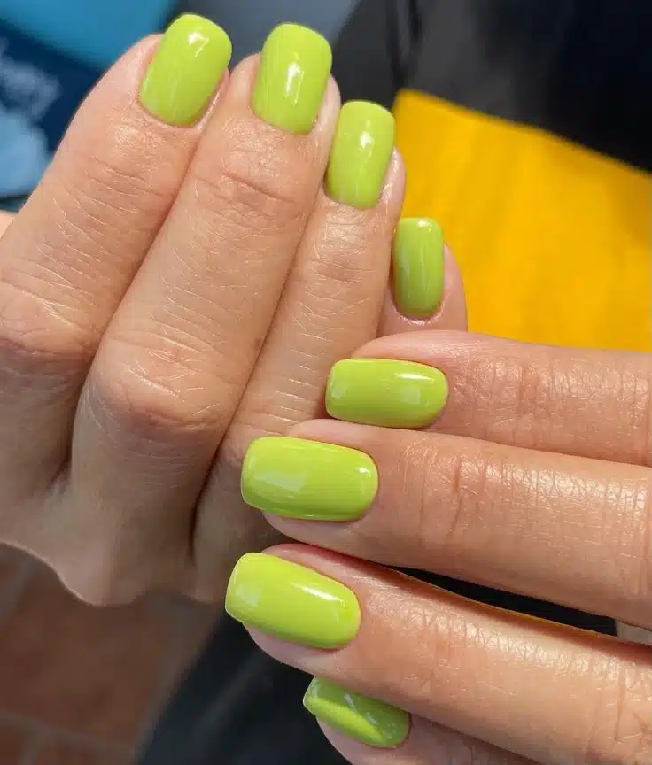 Esmalte verde lima em unhas curtas e quadradas com acabamento brilhoso