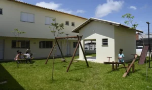 Área de lazer com brinquedos e crianças em condomínio residencial da Semana Minha Casa, Minha Vida.