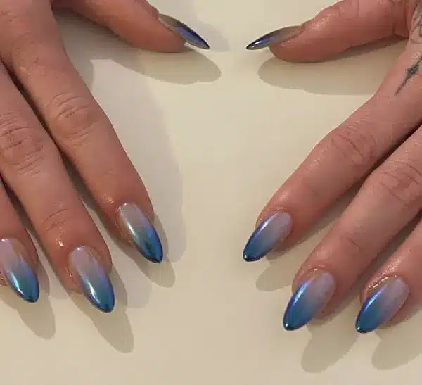 Unhas em formato amendoado com efeito ombré azul, tendência criativa para o inverno de 2025.