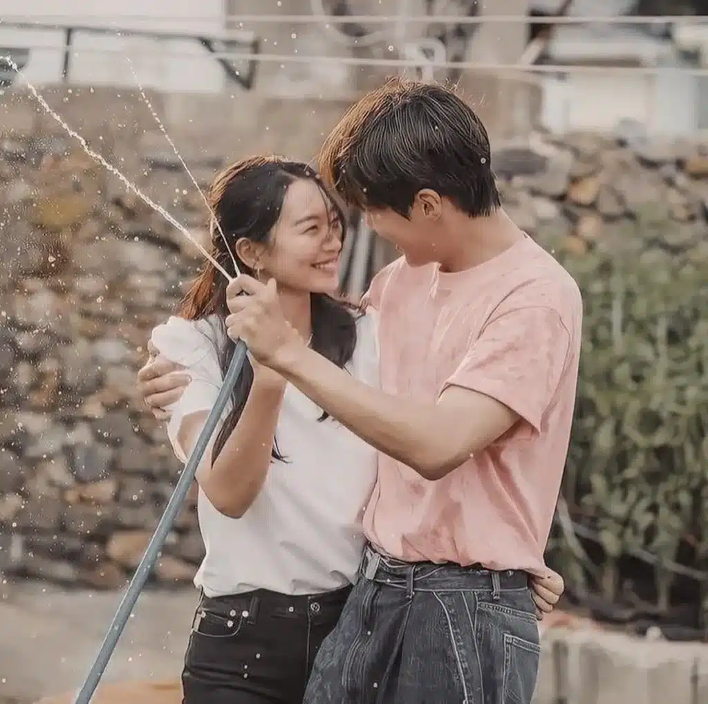 Cena romântica entre o casal protagonista de Hometown Cha-Cha-Cha sorrindo e se divertindo com mangueira d'água.