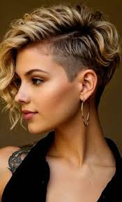 Mulher com corte pixie assimétrico loiro e raspado lateral, usando argola dourada.