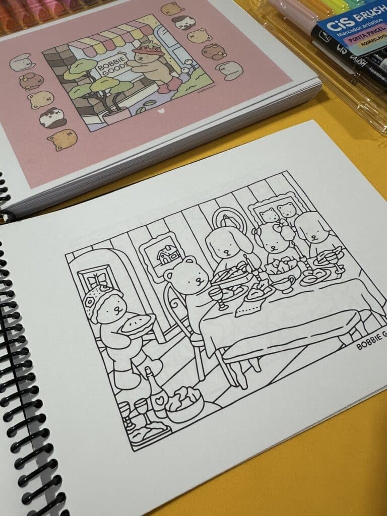 Páginas do livro de colorir Bobbie Goods, com capa rosa e ilustração de mesa posta com ursinhos