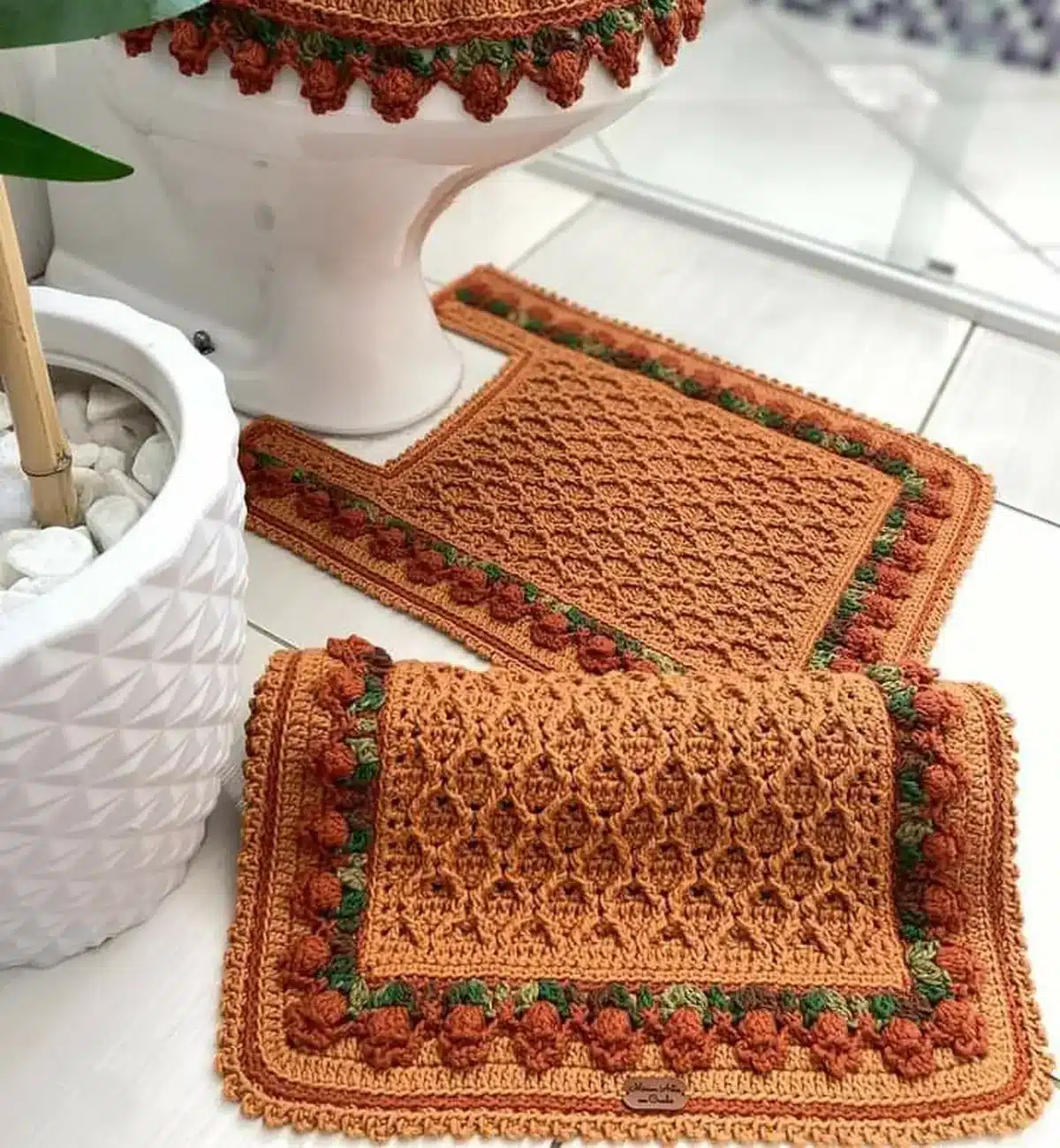 Jogo de banheiro em crochê laranja com detalhes verdes e texturas artesanais, elegante e clássico