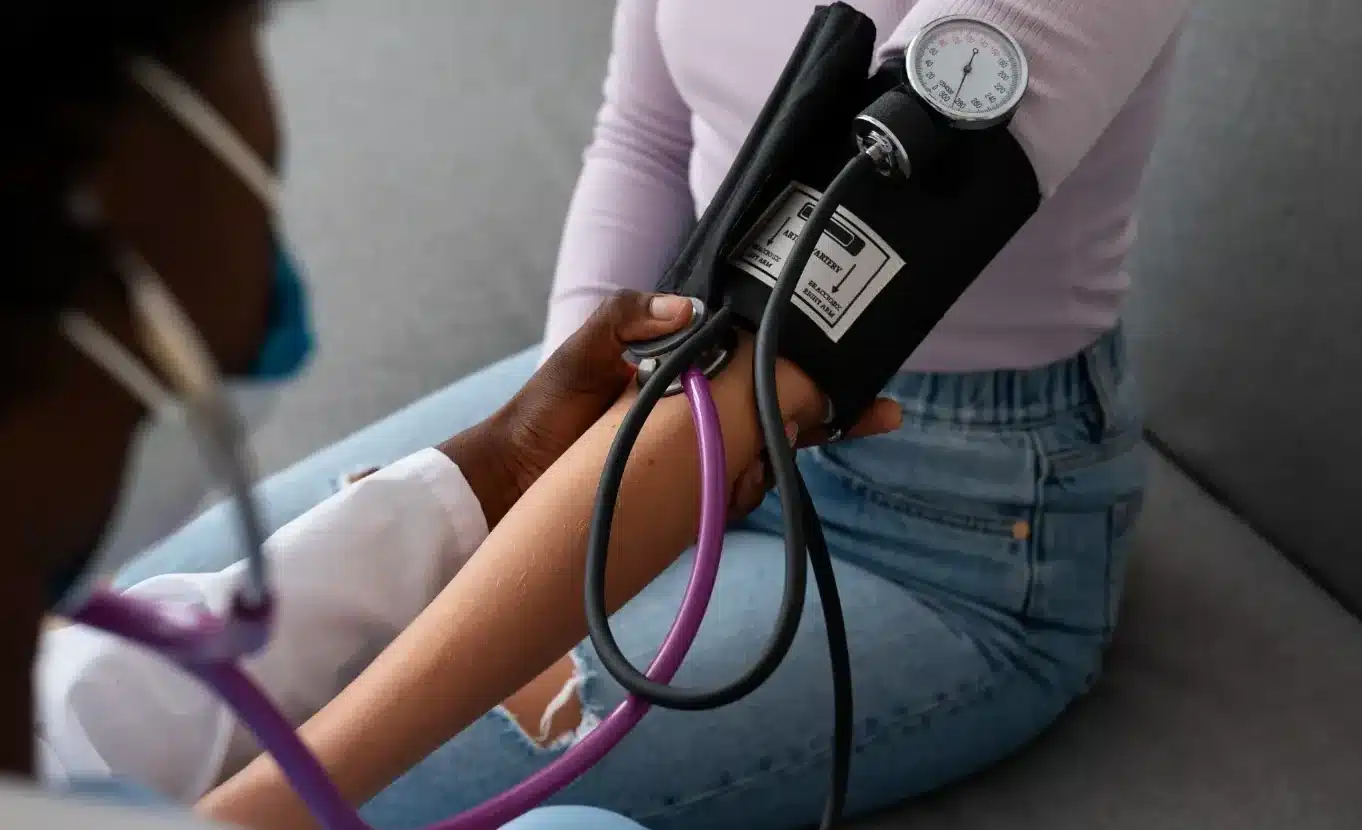 Profissional de saúde medindo a pressão arterial de uma paciente durante atendimento.