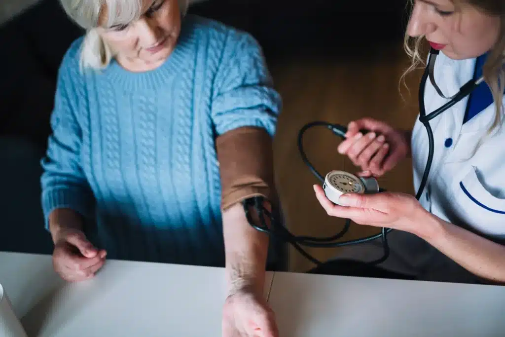  Enfermeira aferindo a pressão arterial de uma paciente idosa durante atendimento.