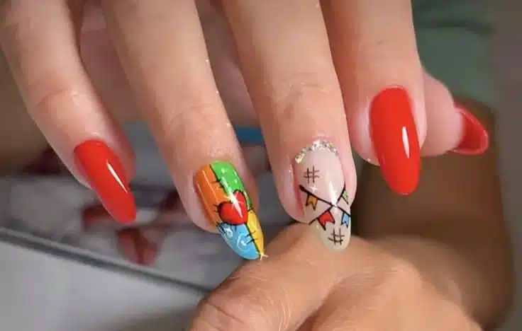 Unhas com nail art colorida e desenhos temáticos de São João, incluindo bandeirinhas e coração