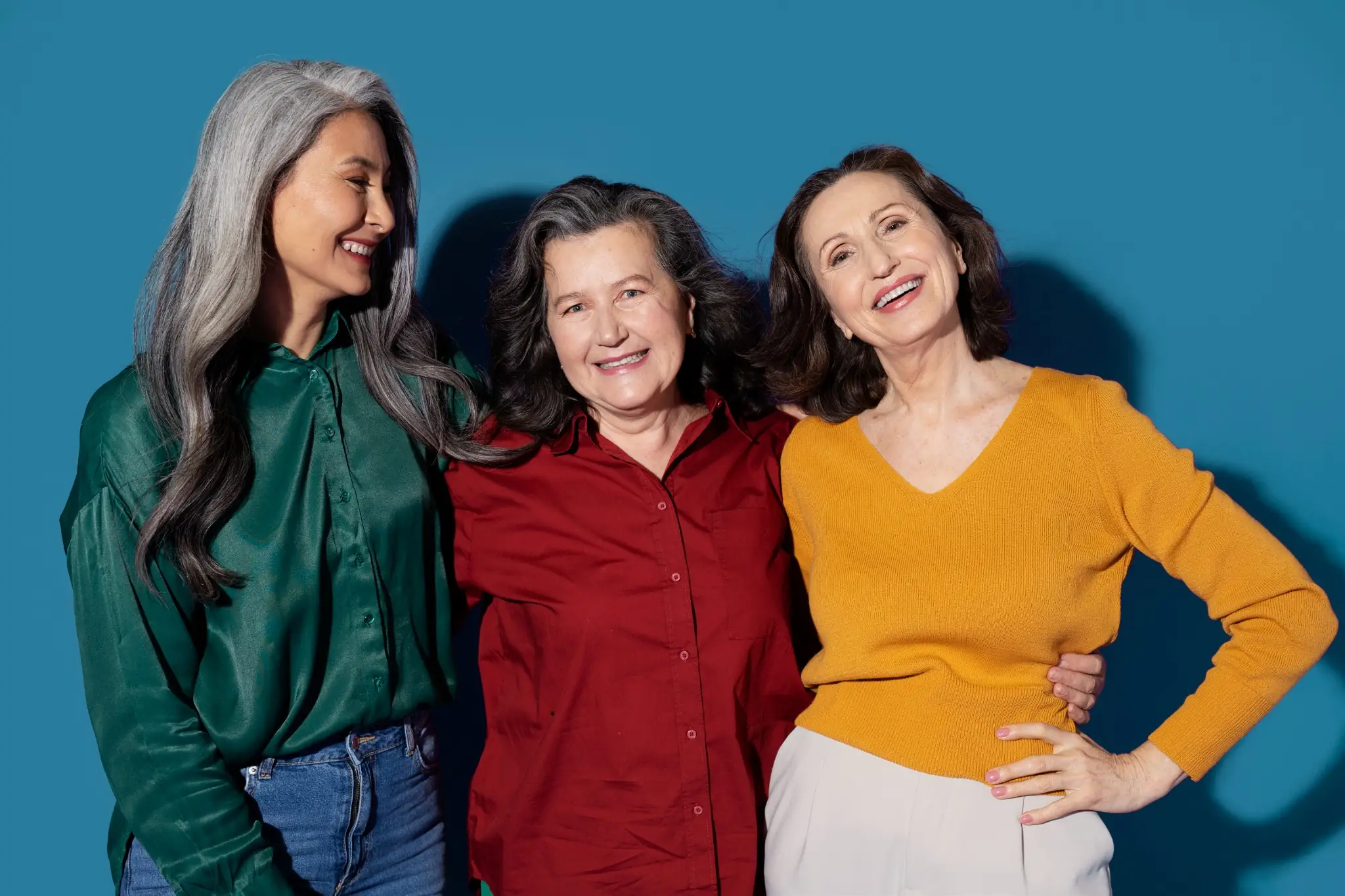 Três mulheres maduras sorrindo, exibindo diferentes cortes e estilos de cabelo