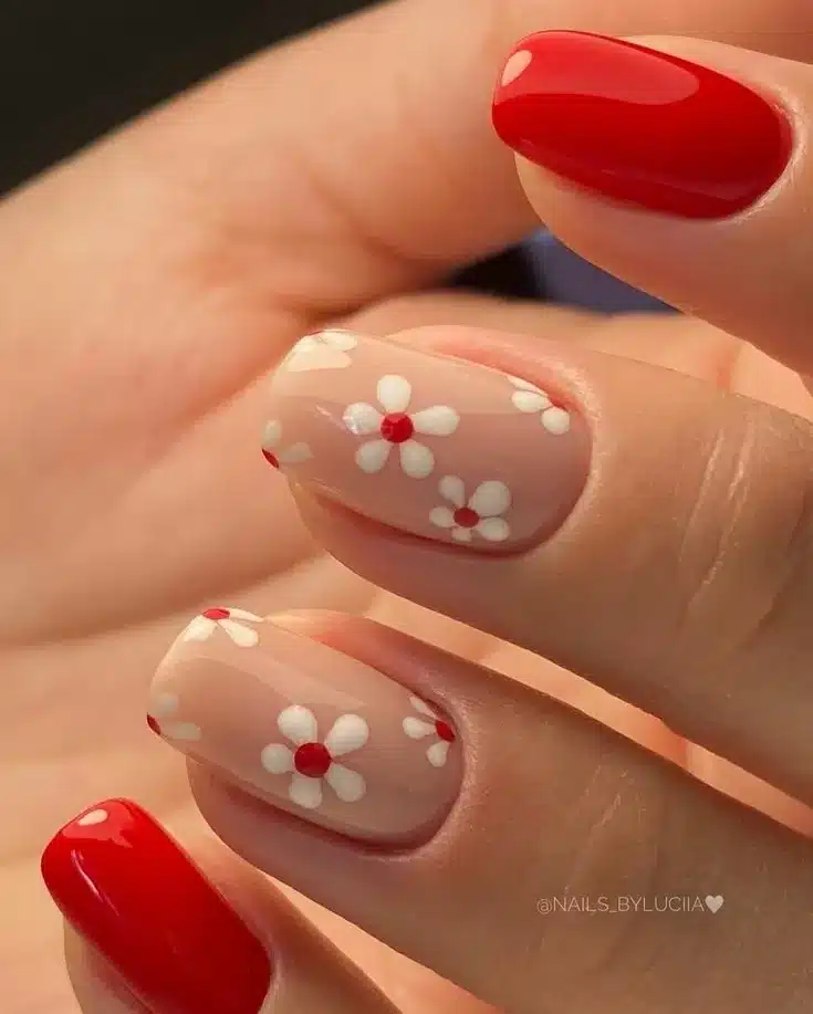 Unhas decoradas com flores brancas e esmalte vermelho vibrante