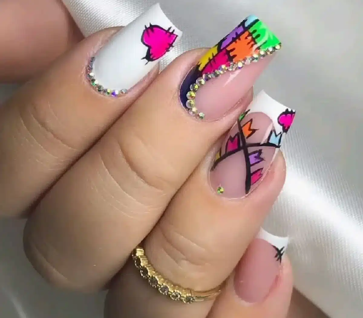 Unhas decoradas coloridas e modernas com pedras brilhantes, design vibrante e detalhes geométricos.